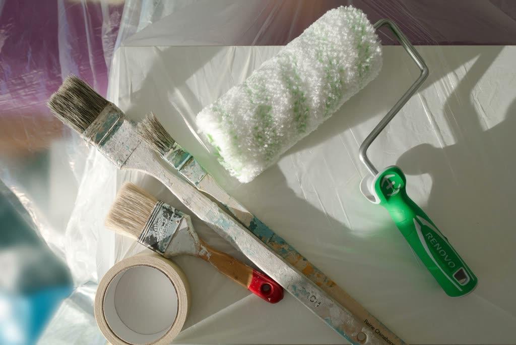 Paint roller and brushes on a painter’s sheet