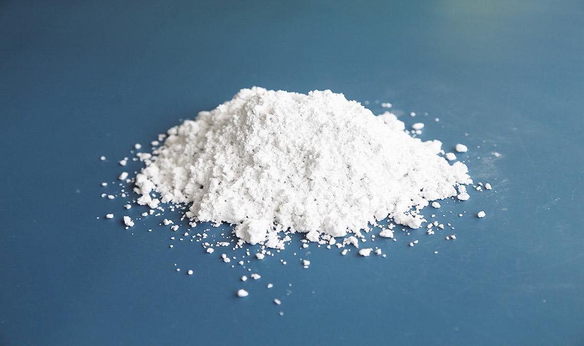 A mound of fine white wollastonite powder on a blue surface
