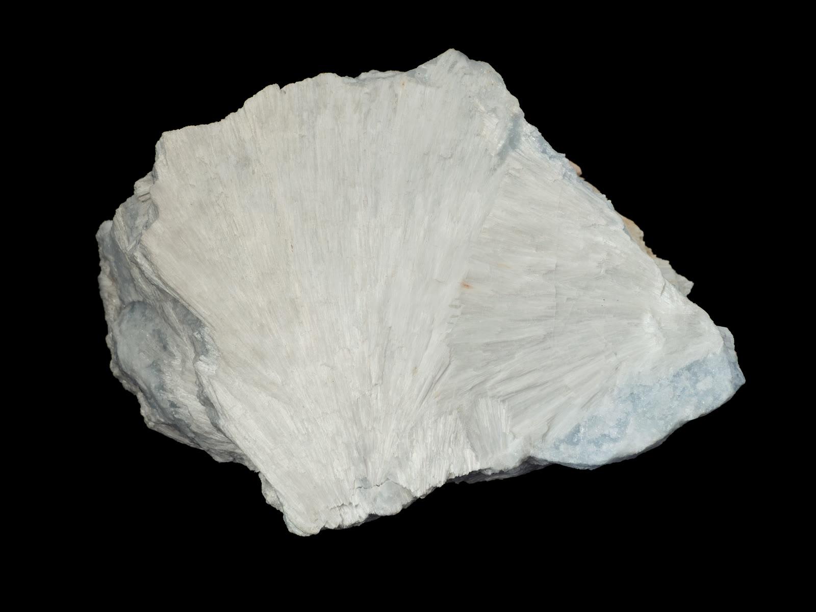 A hand specimen of white wollastonite showing fans of needle-shaped crystals